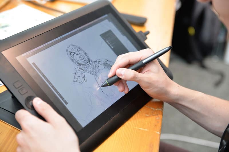artist drawing a comic book character on a digital tablet
